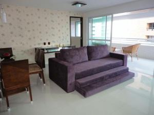 uma sala de estar com um sofá roxo e uma mesa em Apartamento Vista Mar 4 Suítes em Fortaleza