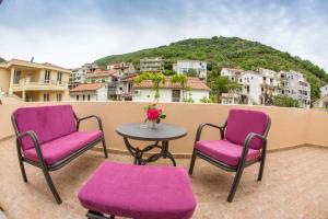 a patio with two chairs and a table with purple chairs at Apartments & Studios Tomanović in Budva