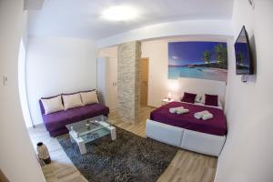 a bedroom with a purple bed and a couch at Apartments & Studios Tomanović in Budva