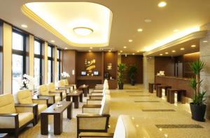 a waiting room with chairs and tables and windows at Hotel Route-Inn Sendainagamachi Inter in Sendai