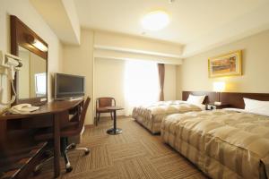 a hotel room with two beds and a desk at Hotel Route-Inn Sendainagamachi Inter in Sendai