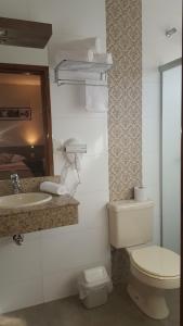 a bathroom with a toilet and a sink at Hotel Recanto in Lajeado