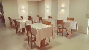 a dining room with white tables and chairs at Hotel Recanto in Lajeado