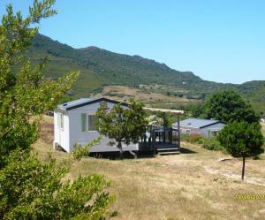 a small white house in a field with a mountain at La Canardiere in Casta