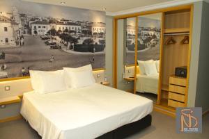 a bedroom with a bed and a poster of a city at Rocha Prestige - Guest House and Suites in Portimão