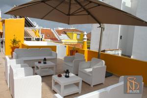 eine Terrasse mit weißen Stühlen und einem Sonnenschirm in der Unterkunft NDS Prestige Guest House and Suites - by Rocha Prestige in Portimão