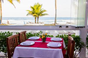 a table with a red table cloth and a view of the beach at Strand Hotel Guarujá Frente Mar in Guarujá