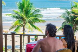 um homem e uma mulher sentados numa varanda com vista para a praia em Strand Hotel Guarujá Frente Mar no Guarujá