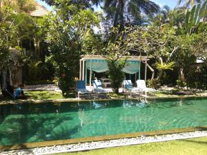 a swimming pool in a yard with chairs and trees at Aquaria Eco Resort in Candidasa