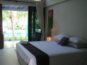 a bedroom with a large white bed and a window at Aquaria Eco Resort in Candidasa