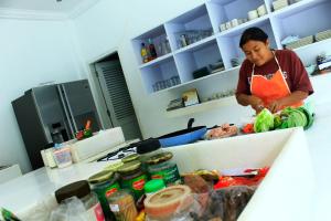 uma mulher numa cozinha a preparar comida num balcão em Villa Putih Lovina em Lovina