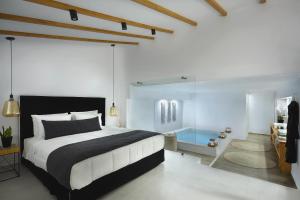 - une chambre avec un grand lit et un mur en verre dans l'établissement Callia Caves - Adults Only, à Fira