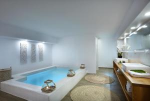 een badkamer met een zwembad en een wastafel bij Callia Caves - Adults Only in Fira