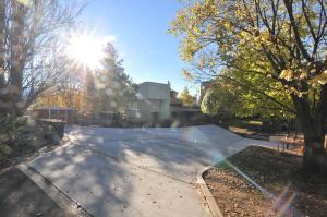 an empty street with the sun shining through trees at Leski Club in Jindabyne