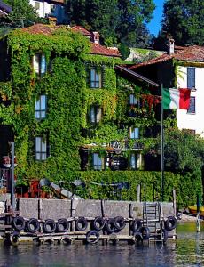 ein von Efeu bedecktes Gebäude mit einer Flagge im Wasser in der Unterkunft Pescallo Apartments in Bellagio