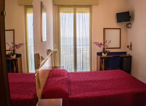 a hotel room with a red bed and a window at Hotel Brasilia in Lido di Classe
