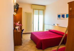 a hotel room with a red bed and a window at Hotel Brasilia in Lido di Classe