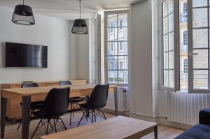 a dining room with a table and chairs and windows at L'Annexe in Saint Malo