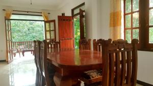 a dining room with a wooden table and chairs at Villa Happy Home in Bentota