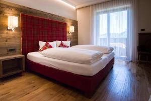 a bedroom with a large bed with a red headboard at Hotel Garni Vigilhof in Lana