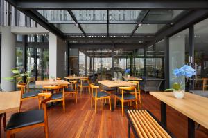 un restaurante con mesas y sillas de madera y ventanas en BATIQA Hotel Jababeka Cikarang en Cikarang