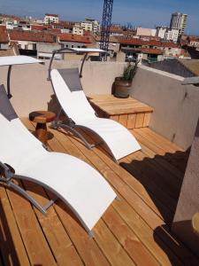 a balcony with white chairs and a table on a roof at L'Atypique in Sète