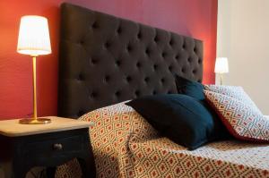 a bed with a large black headboard and a table with a lamp at Retrò B&B in Pisa