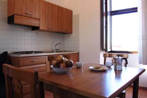 a kitchen with a wooden table with a bowl of fruit on it at Residence Albachiara in Marina di Camerota