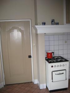 een kleine keuken met een fornuis en een deur bij Vakantiehuis Den Bosch in Den Bosch