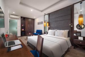a bedroom with a bed and a desk with a laptop at Bonsella Hotel in Hanoi
