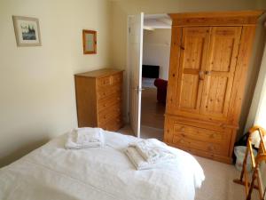 ボスキャッスルにあるCourtyard Farm Cottages Mill Endの白いベッドと木製キャビネット付きのベッドルーム1室が備わります。