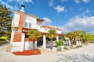 a house with palm trees in front of it at Apartments Katarina in Veli Rat