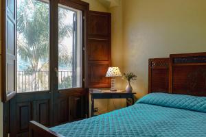 a bedroom with a bed and a table with a lamp at La Parrinara in Francavilla di Sicilia +25 photos