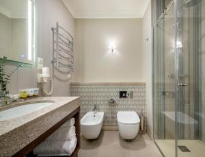 a bathroom with a sink, toilet and bathtub at Ratonda Centrum Hotels in Vilnius