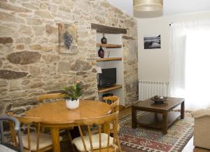 a living room with a wooden table and a stone wall at Casa Playa de Balares in Ponteceso