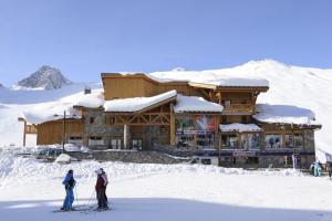two people on skis in front of a ski lodge at CGH Résidences & Spas Le Jhana in Tignes