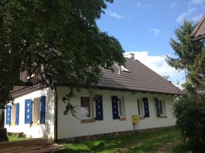 a small white house with blue shutters at Muzyczna Zagroda in Pietzonken