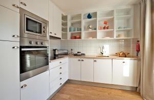 a white kitchen with white cabinets and a microwave at The Salty Lodge in Lagos