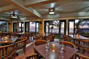 a restaurant with wooden tables and chairs and windows at The Jayakarta Anyer in Anyer