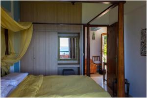 a bedroom with a canopy bed with a view of the ocean at Panorama Notos in Nótos