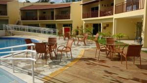 un patio con mesas y sillas junto a una piscina en Flat 259 localizado no Condomínio Solar Água, en Pipa