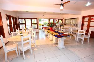 Benko´s Praia Hotel في بورتو سيغورو: غرفة طعام مع طاولات وكراسي عليها طعام