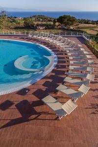a row of lounge chairs next to a swimming pool at LUZIA AGRIRESORT - Piscina Panoramica e vista Mare a Capo Vaticano in Capo Vaticano