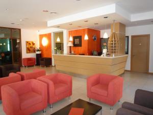 uma sala de espera com cadeiras vermelhas e um balcão em Hotel San Francisco em Lignano Sabbiadoro