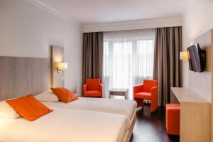 a hotel room with two beds and two orange chairs at Hampshire Hotel – Voncken Valkenburg in Valkenburg