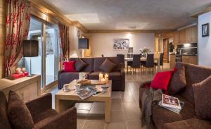 ein Wohnzimmer mit Sofas und einem Tisch sowie eine Küche in der Unterkunft CGH Résidences & Spas Les Chalets de Léana in Les Carroz d'Araches