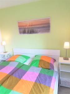 a bed with a colorful comforter in a bedroom at Ferienwohnung Krabbentaucher 2 in Neßmersiel
