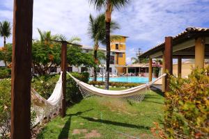 a hammock in front of a house with a pool at Benko´s Praia Hotel in Porto Seguro