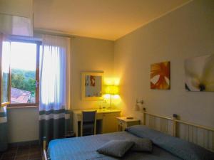 una camera con letto, scrivania e finestra di Hotel Le Renaie a San Gimignano