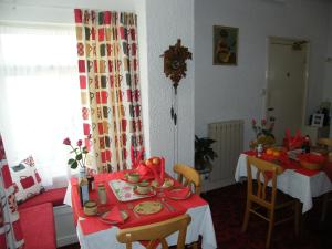 un comedor con 2 mesas y un mantel rojo en El Tabora Guest House en St. Peter Port